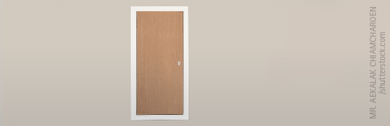 Kleine Tür aus Holz auf weißer Wand.