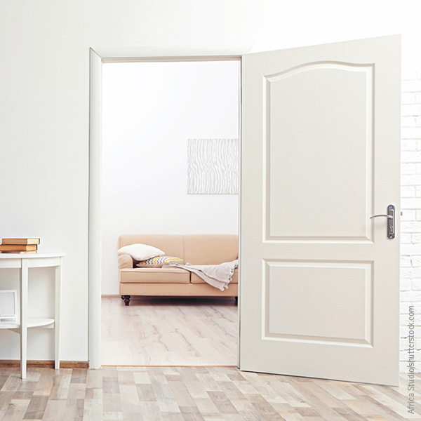 Weiße Tür eröffnet Blick auf gemütliche Couch im Nebenzimmer.