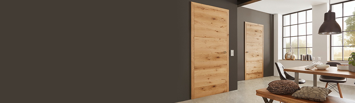 Zwei Holztueren in einem weiss-braun gestrichenen Raum mit moderner Einrichtung mit einzelnen Holzelementen.